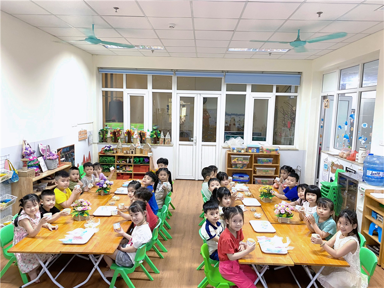 A group of children sitting at tables in a classroom

Description automatically generated
